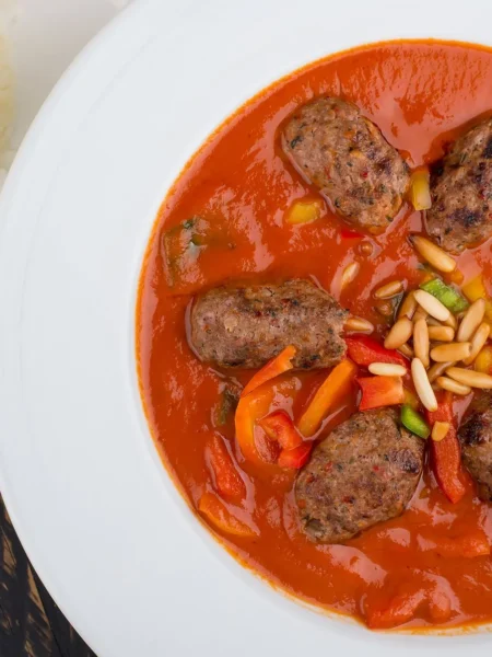 easy meatball and couscous soup recipe with small beef meatballs, fluffy couscous, and wilted spinach in a clear tomato broth