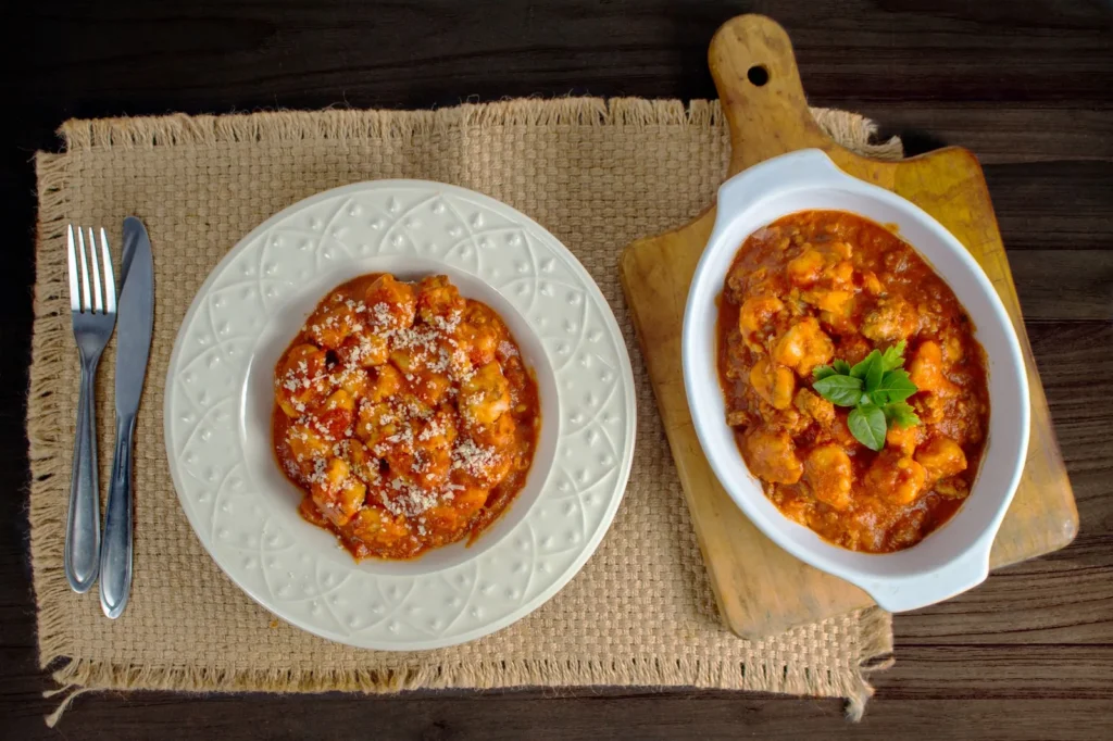 gnocchi bolognese recipe with pillowy potato gnocchi in a rich tomato beef sauce topped with grated parmesan in a skillet