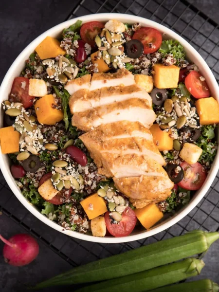 high protein lunch bowls for weight loss with grilled chicken, quinoa, avocado, and cherry tomatoes in a white bowl