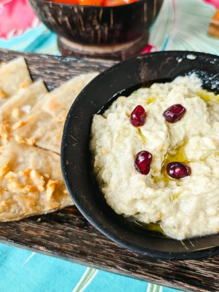 hummus recipe with roasted garlic served in a shallow bowl with olive oil drizzle and smoked paprika on top