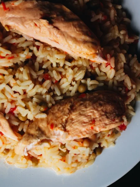 instant pot chicken and rice recipe easy with browned chicken thighs, separate white rice grains, and green peas in a stainless pot