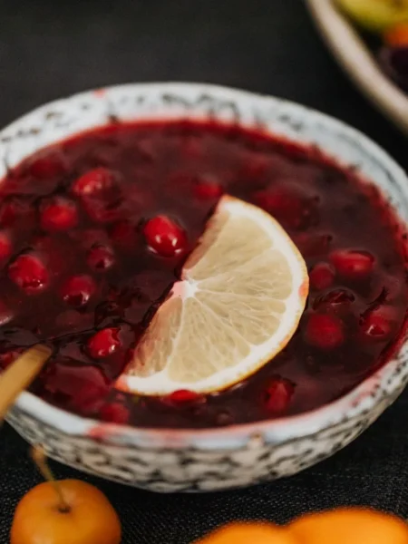 instant pot cranberry sauce in a white bowl with whole and burst red cranberries and orange zest strips