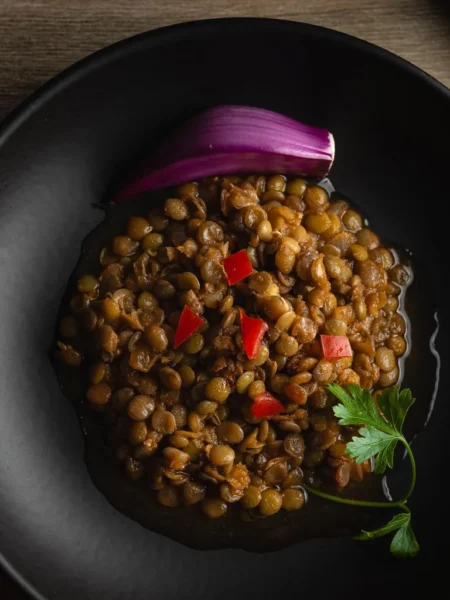 instant pot lentils in a white bowl with olive oil sheen, cumin specks, and chopped parsley on top