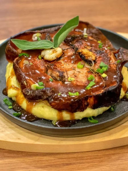 instant pot pork chops recipe juicy with seared bone-in chops in glossy brown gravy and parsley on a white plate