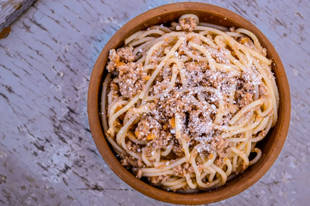 instant pot spaghetti recipe one pot with tender noodles in red tomato beef sauce topped with parmesan in a steel insert
