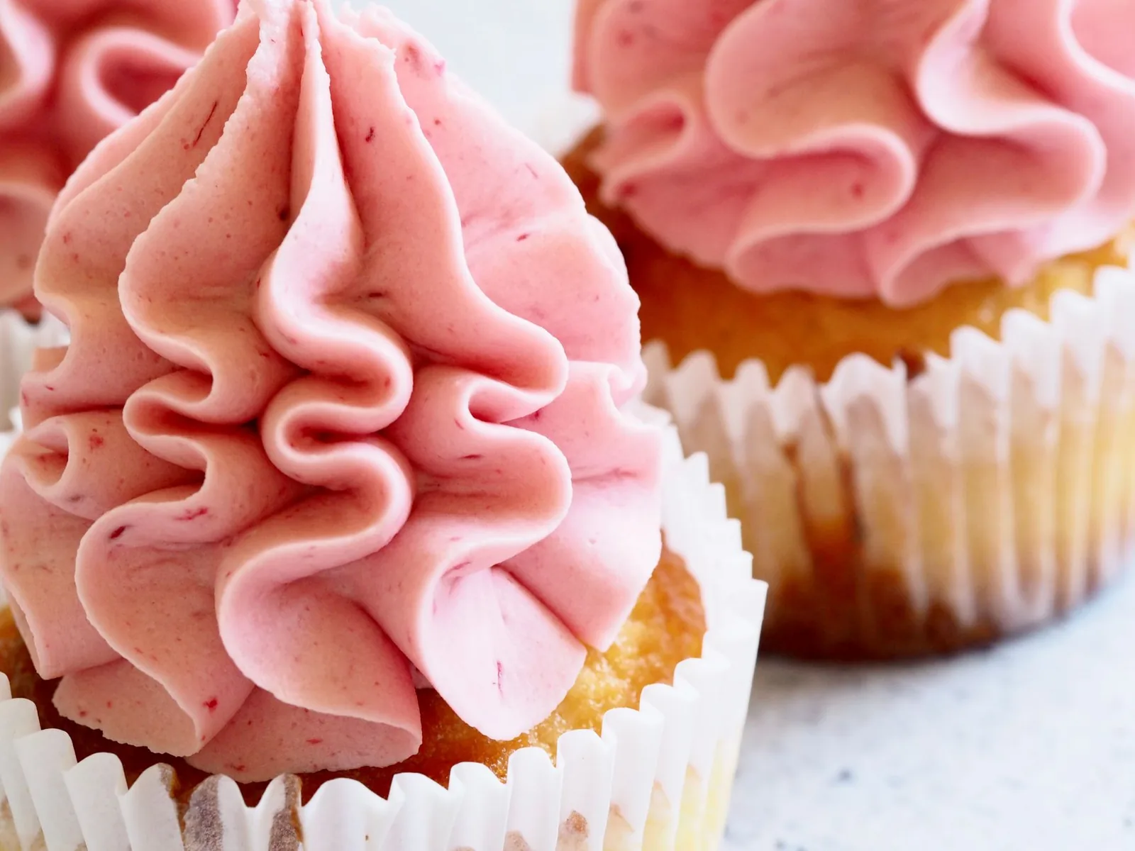golden lemonade cupcakes with swirled lemon frosting on white tray