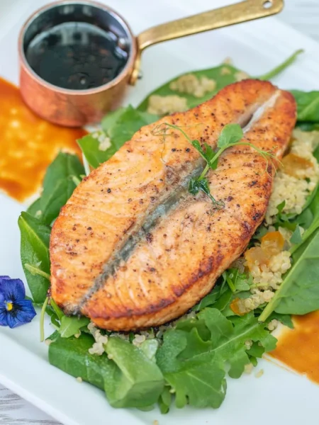 low sodium dinner recipe for heart health showing baked lemon thyme salmon on quinoa with wilted spinach
