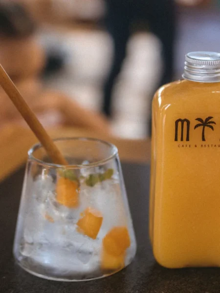 mango agua fresca recipe in a clear glass with diced mango pieces and ice cubes on a wooden table