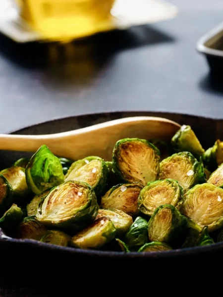 maple roasted brussels sprouts recipe with crisp caramelized leaves, toasted pecans, and a glossy maple glaze on a white plate
