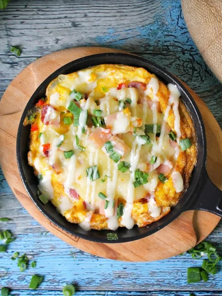 mexican corn bread recipe baked in a cast iron skillet with corn kernels, green chiles, and melted cheddar on top