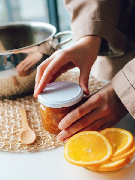 no pectin citrus marmalade in a glass jar with sliced orange and lemon peel in amber syrup on linen