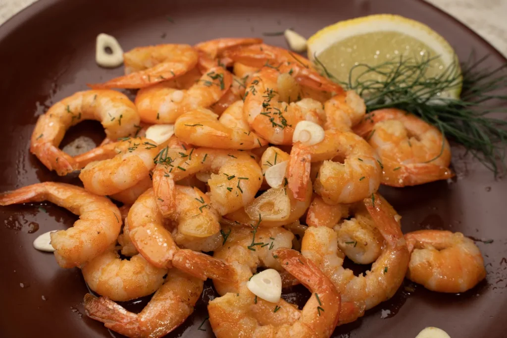 one pan lemon garlic shrimp dinner with pink shrimp in garlic lemon butter sauce in a skillet topped with parsley