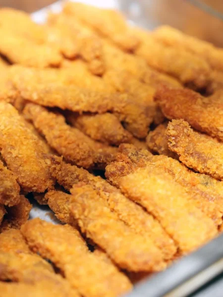 oven baked zucchini fries on a tray with golden panko parmesan coating and a side of dip