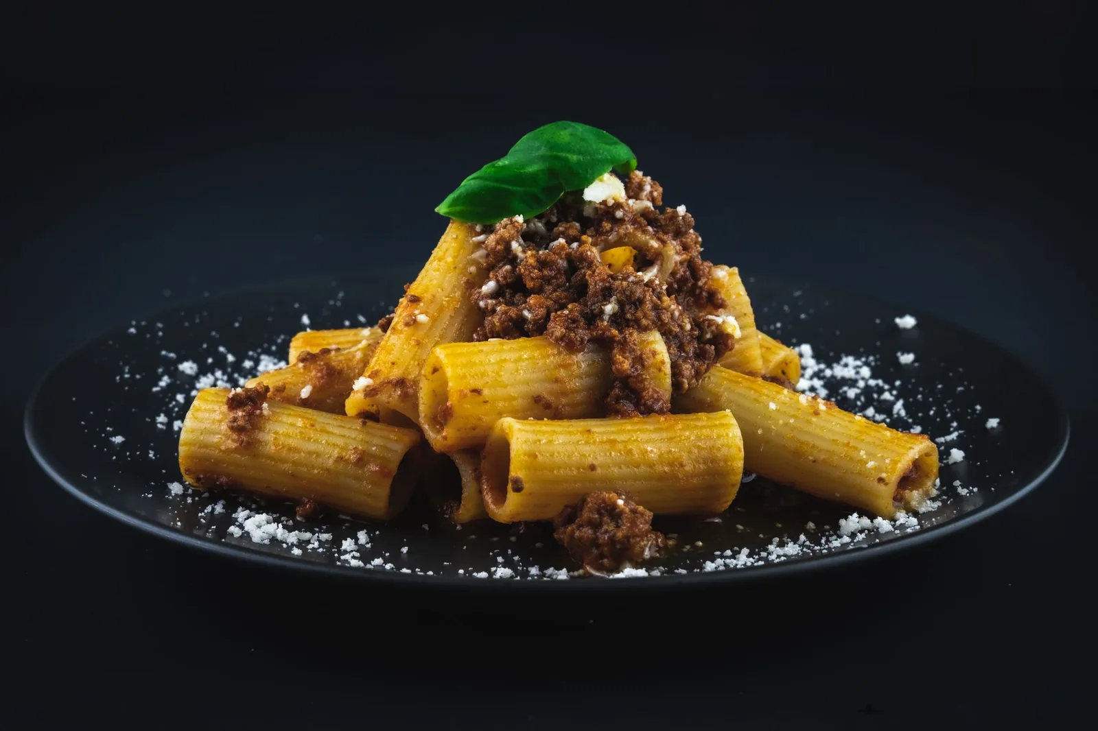 rigatoni in thick red meat sauce with parmesan on top