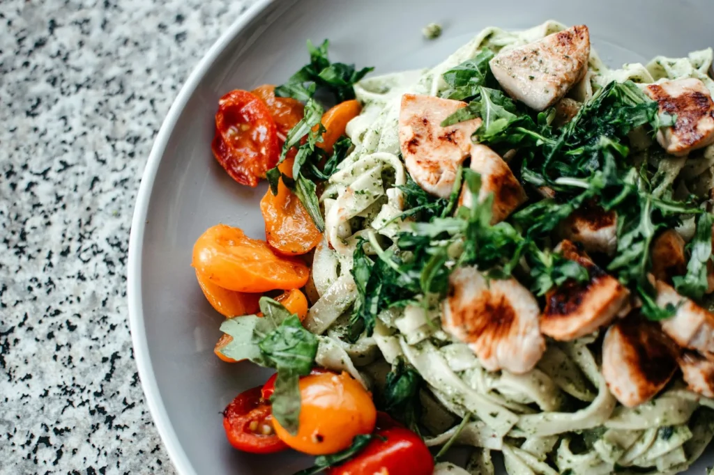 pesto orzo salad recipe in a white bowl with cherry tomatoes, parmesan, and torn basil