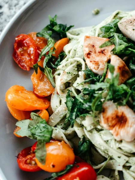 pesto orzo salad recipe in a white bowl with cherry tomatoes, parmesan, and torn basil