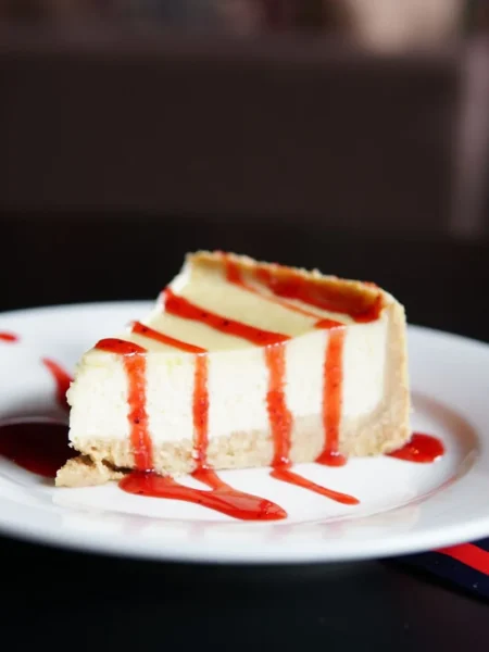 pumpkin pie cheesecake bars with graham crust, spiced pumpkin top, and creamy cheesecake layer on a white plate