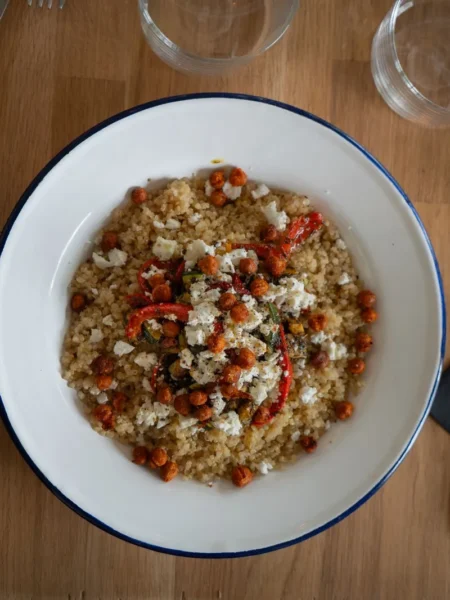 quinoa salad recipe for healthy lunch with cucumber, cherry tomato, chickpeas, and parsley in lemon dressing on a white plate