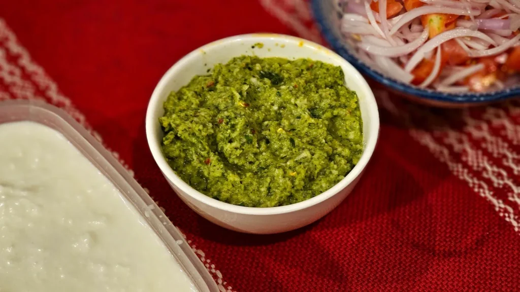recipe of dhaniya chutney as a bright green coriander dip in a white bowl with lemon wedge