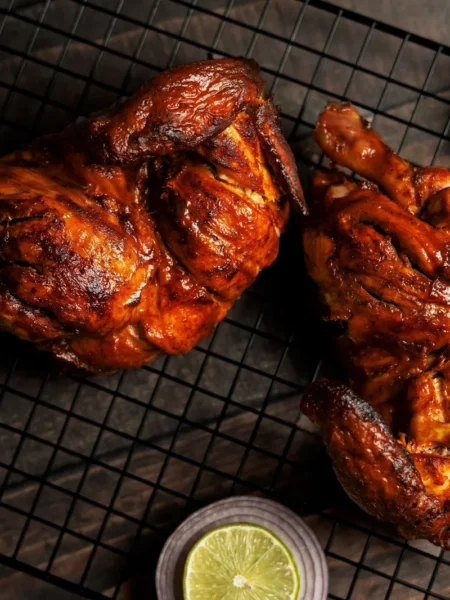 roasted chicken leg quarters with golden crisp skin and lemon wedges on a wire rack