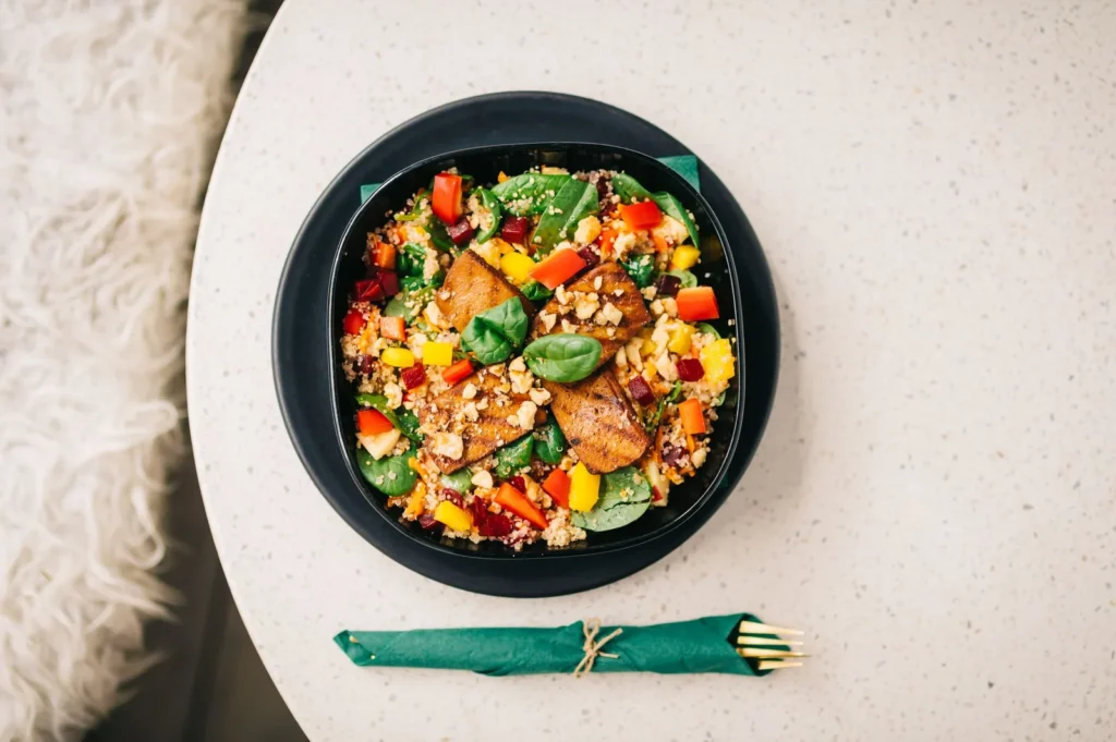 roasted sweet potato salad with quinoa in a white bowl with golden potato cubes, fluffy quinoa, parsley, and feta