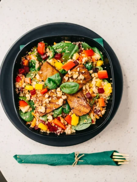 roasted sweet potato salad with quinoa in a white bowl with golden potato cubes, fluffy quinoa, parsley, and feta