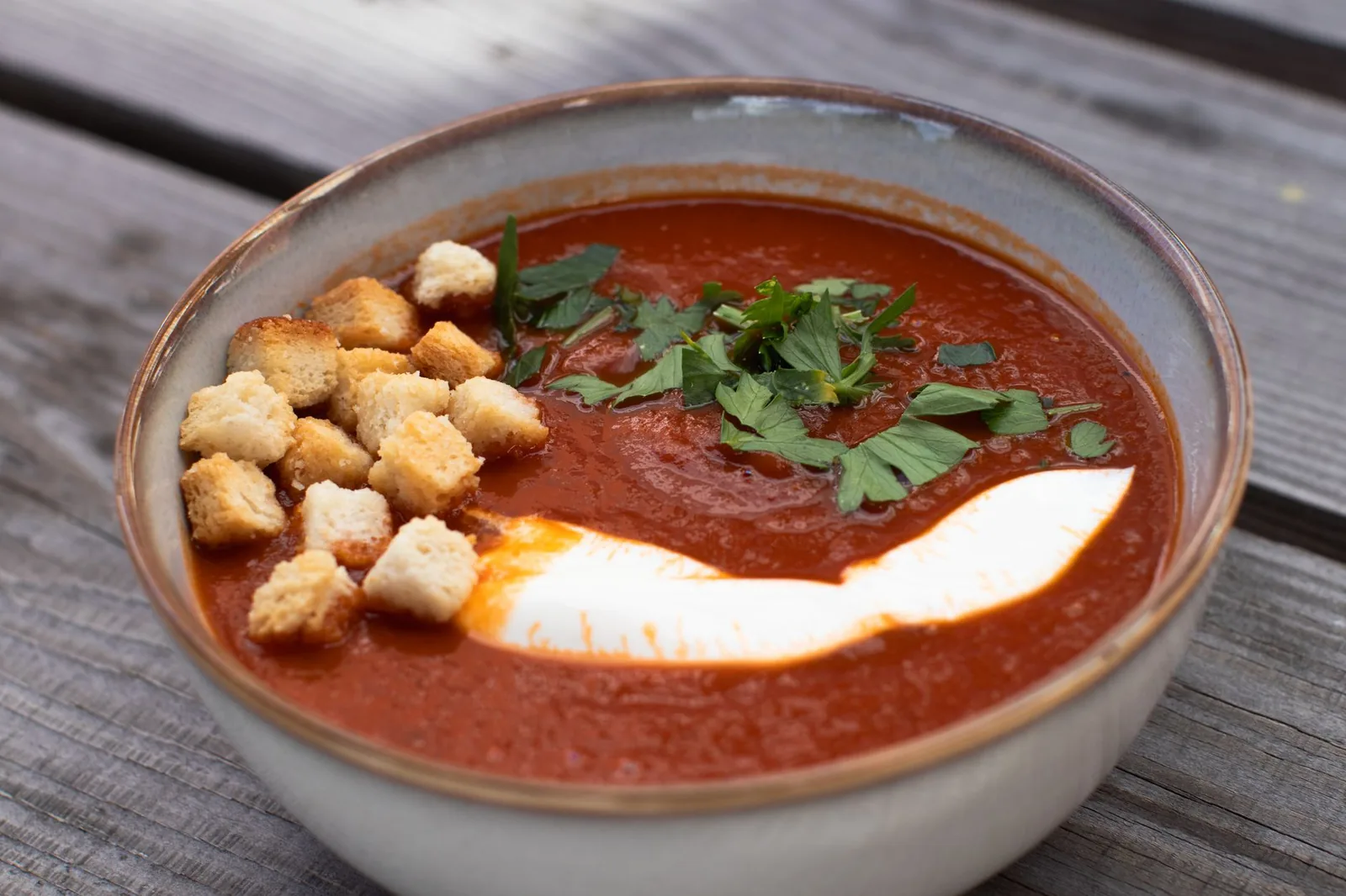 bowl of roasted tomato soup with cream swirl and basil