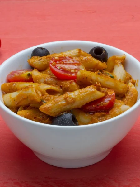 rotini pasta salad recipe with cherry tomatoes, cucumber, red onion, olives, and parmesan in a white bowl