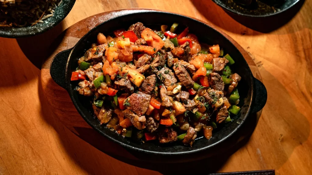 sausage and peppers pasta in a skillet with rigate, seared Italian sausage, and red yellow green bell peppers in tomato sauce