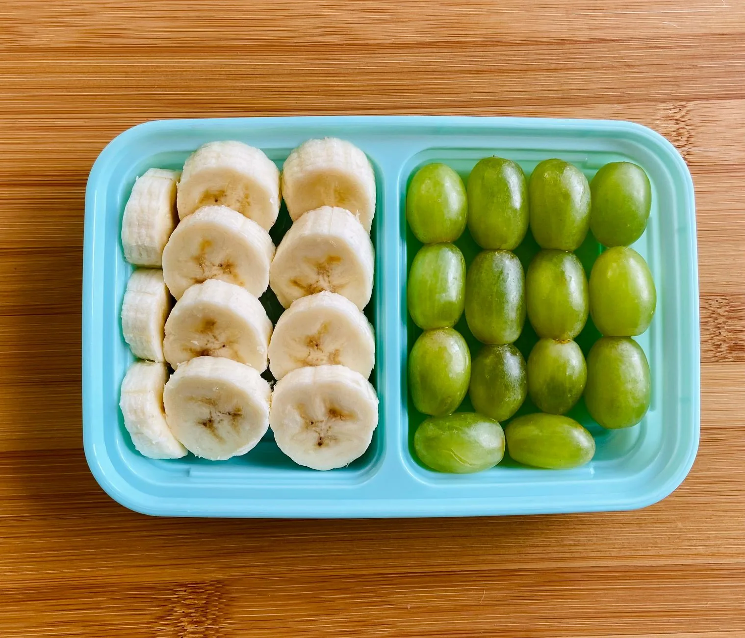 school lunch ideas for picky eaters with separate mini pitas, cheddar cheese, cucumber, and grapes in a divided box