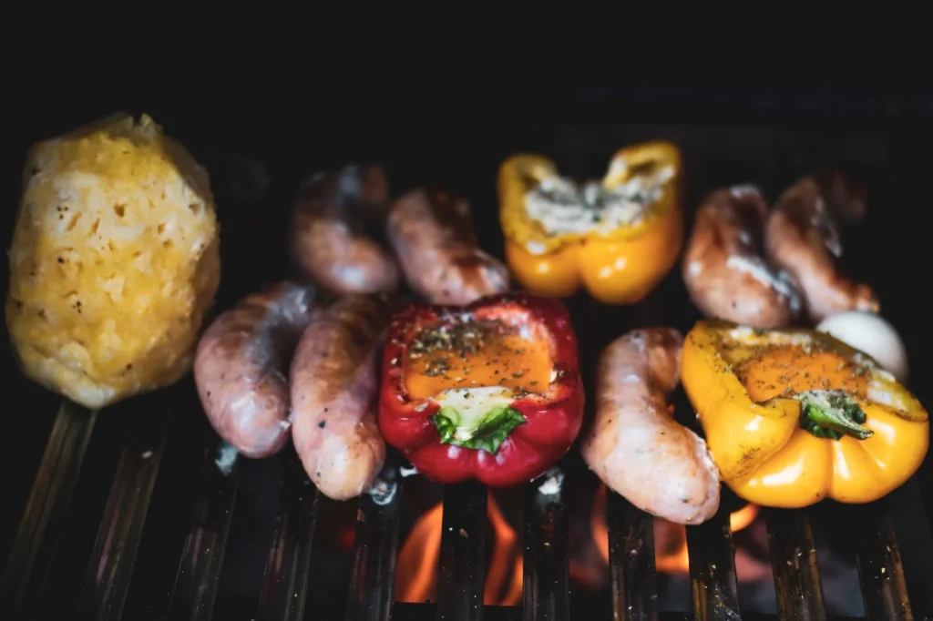 sheet pan sausage and peppers dinner with browned Italian sausages, red yellow green peppers, and soft onions on a rimmed baking tray