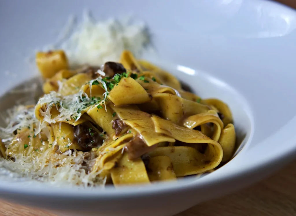 short rib ragu recipe with shredded beef and red tomato sauce over wide pappardelle pasta topped with parmesan