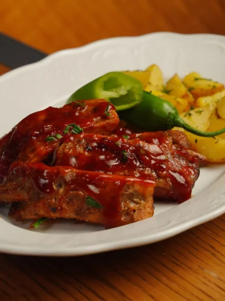 slow cooker baby back ribs glazed with sticky barbecue sauce and caramelized edges on a white platter