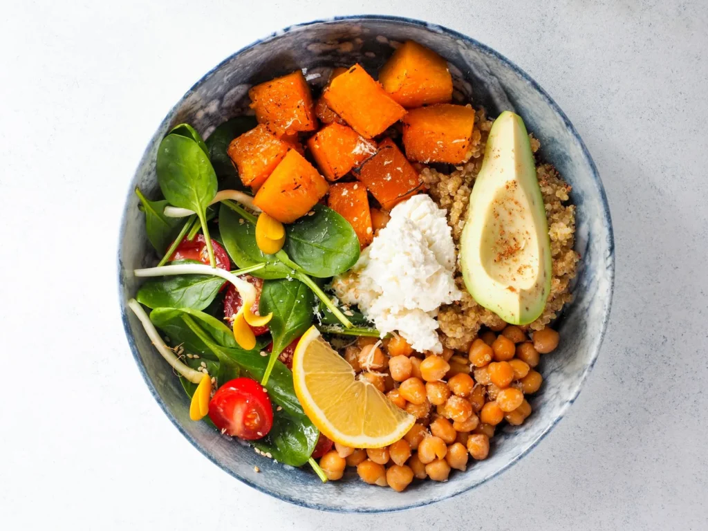 southwest quinoa bowl recipe for lunch with fluffy quinoa, black beans, corn, red pepper, and avocado slices in a white bowl