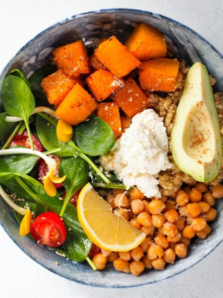 southwest quinoa bowl recipe for lunch with fluffy quinoa, black beans, corn, red pepper, and avocado slices in a white bowl