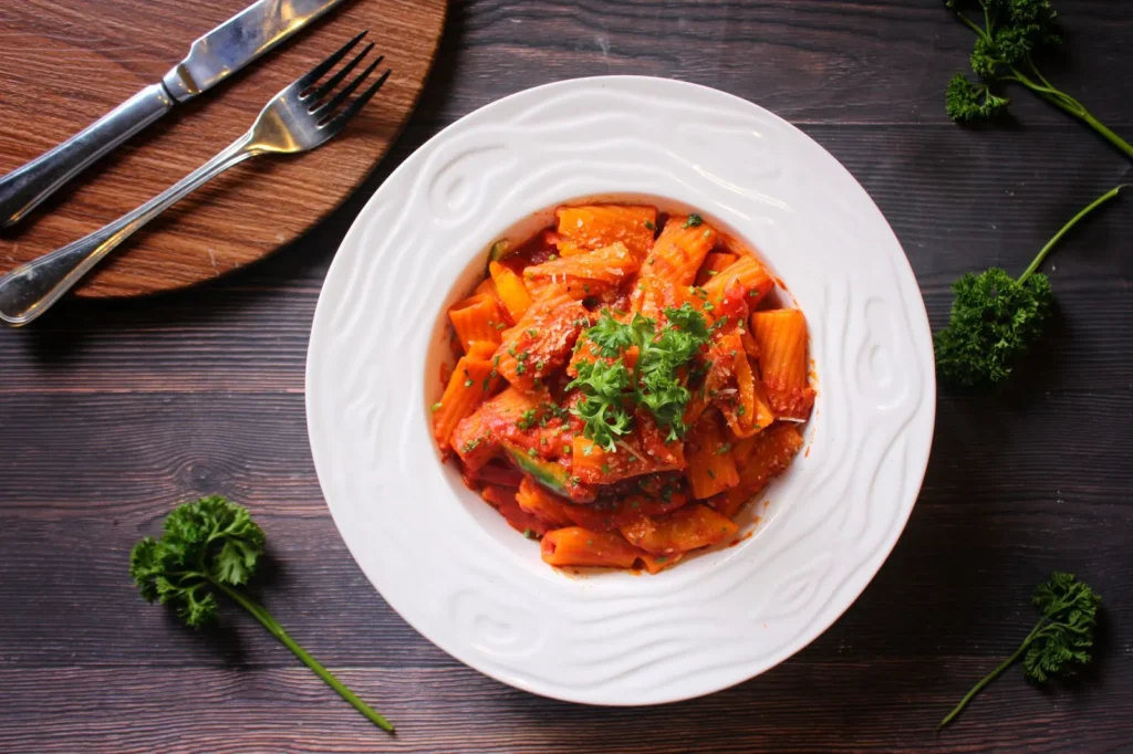 spicy rigatoni with ground pork in a wide pan with golden pork bits, orange cream sauce, and parsley on top