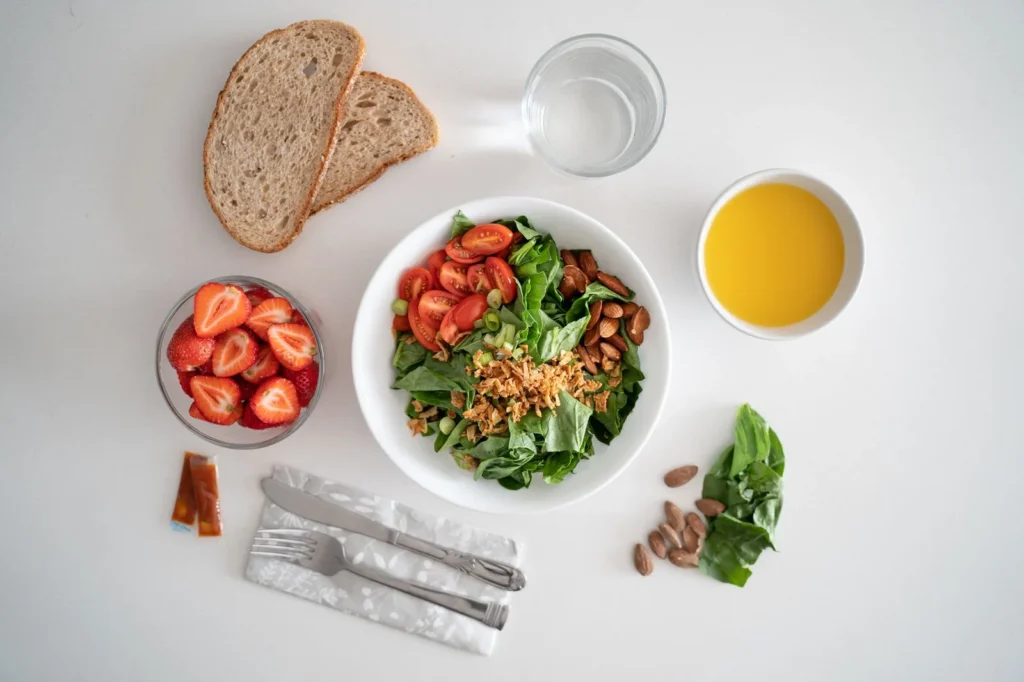 spinach and arugula salad in a white bowl with toasted almonds and shaved parmesan