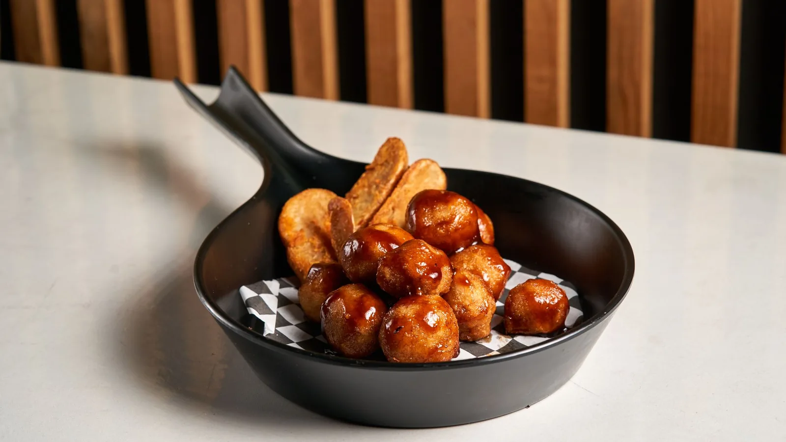 sticky honey glazed meatballs in a skillet with sesame seeds