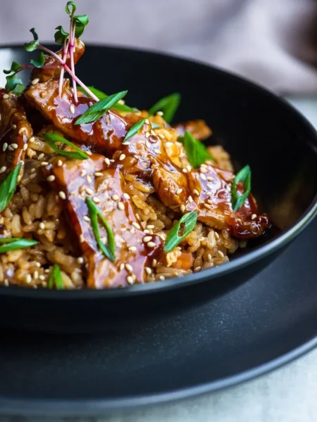 teriyaki ground beef bowls with glossy beef crumbles, white rice, shredded cabbage, carrots, and sesame seeds in a shallow bowl