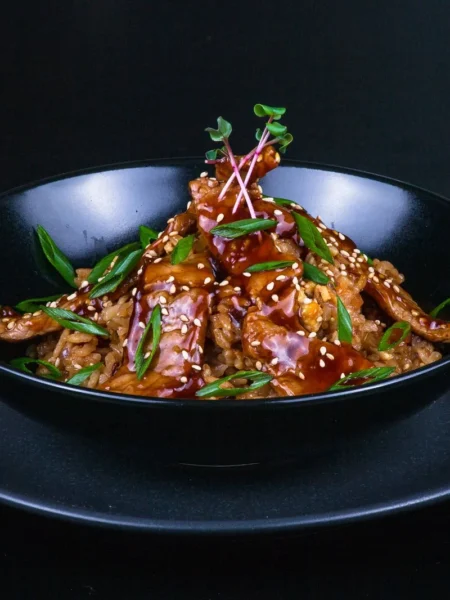 weight watchers teriyaki chicken with glossy sticky glaze on seared chicken strips topped with sesame seeds and green onions in a skillet