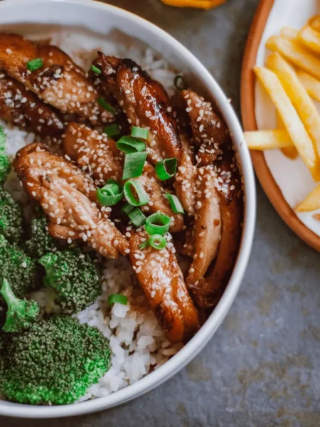 work lunch ideas that reheat well shown as a packed bowl with brown rice, seared chicken in soy honey sauce, and bright broccoli